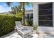 Outdoor patio area featuring a comfortable lounge chair, greenery, and a beautiful, sunny day at 751 Capri Isles Blvd # 108, Venice, FL 34292