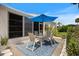 Outdoor patio with a table and chairs under a blue umbrella, surrounded by lush landscaping at 751 Capri Isles Blvd # 108, Venice, FL 34292