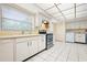 Spacious kitchen featuring white cabinets, tile floors, stainless steel range and dishwasher, and laundry closet at 844 Senda Plata # 27, Venice, FL 34293