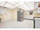 Bright kitchen with stainless steel refrigerator, white cabinets, and white tiled floor at 844 Senda Plata # 27, Venice, FL 34293