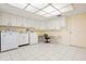 Sunlit laundry room featuring tile floors, white cabinets, stainless steel appliances, and a sewing area at 844 Senda Plata # 27, Venice, FL 34293
