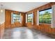 Living room features wood paneling, grey vinyl flooring, and natural light from three windows overlooking the yard at 844 Senda Plata # 27, Venice, FL 34293