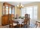 A formal dining room with a chandelier, china cabinet and a table set for six next to a large bay window at 925 S Doral Ln, Venice, FL 34293