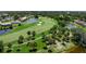 Aerial view of a verdant golf course with sand traps, palm trees, and serene water features in a lush, upscale community at 925 S Doral Ln, Venice, FL 34293
