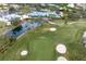 Scenic aerial view of a golf course with lush greens, sand bunkers, and a well-appointed clubhouse overlooking a tranquil pond at 925 S Doral Ln, Venice, FL 34293