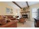 Living room featuring vaulted ceilings with wood beams, a stone fireplace and a leather couch at 925 S Doral Ln, Venice, FL 34293