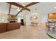 Open-concept living and dining area with stone fireplace, exposed beams, and tile flooring at 925 S Doral Ln, Venice, FL 34293