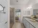 Bathroom featuring granite counters, double sinks, a shower, and an open view to the main bedroom at 9917 Haze Dr, Venice, FL 34292