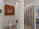 Bathroom showcasing the toilet, storage, and tiled walk-in shower with glass door to the main bedroom at 9917 Haze Dr, Venice, FL 34292