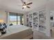 Bright bedroom featuring built-in bookshelves and sliding glass door to screened patio at 9917 Haze Dr, Venice, FL 34292
