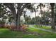 Professionally landscaped yard with colorful plants, mature trees, and a well-maintained sidewalk at 9917 Haze Dr, Venice, FL 34292