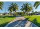 Scenic park view with lush green grass, mature palm trees, and comfortable benches at 9917 Haze Dr, Venice, FL 34292