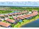 Aerial view of a community featuring homes with terracotta roofs and landscaped yards near a lake at 10061 Cozy Grove Dr, Venice, FL 34293