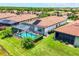 Aerial view of a home with a screened-in pool surrounded by lush greenery and landscaping at 10061 Cozy Grove Dr, Venice, FL 34293