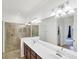 Bathroom with a double vanity, walk-in shower, tile flooring, and ample lighting fixtures at 10061 Cozy Grove Dr, Venice, FL 34293
