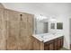 Bathroom with a large mirror over double sinks, and a shower tiled in warm, earthy tones at 10061 Cozy Grove Dr, Venice, FL 34293