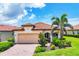Charming single-story home featuring a red tile roof, paver driveway, and lush tropical landscaping at 10061 Cozy Grove Dr, Venice, FL 34293