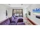 Comfortable living room features a purple sofa and sliding glass doors leading to the pool at 10061 Cozy Grove Dr, Venice, FL 34293