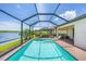 Relaxing screened-in pool area overlooks a serene lake with lounge chairs at 10061 Cozy Grove Dr, Venice, FL 34293