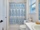 Bright bathroom showcasing a shower with a patterned curtain, vanity with sink, and a sunlit window at 11560 Tapestry Ln, Venice, FL 34293