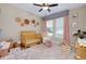 Bedroom with stylish decor including a crib, patterned rug, pink accents, and natural light from the windows at 11560 Tapestry Ln, Venice, FL 34293