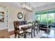 Open dining room area with wood floors, stylish chandelier, buffet, round mirror and view of the screened in lanai at 11560 Tapestry Ln, Venice, FL 34293