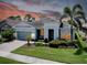Single-story home showing landscape, yard, and custom exterior lighting with warm, inviting glow at 11560 Tapestry Ln, Venice, FL 34293