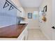 Laundry room featuring tile floors, blue backsplash, a sink with butcher block countertop, and white cabinets at 11560 Tapestry Ln, Venice, FL 34293