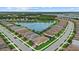 Aerial neighborhood view showcasing houses surrounding a lake with a fountain, with mature trees and landscaping at 11970 Lovegrass St, Venice, FL 34293