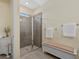 Bright bathroom featuring a walk-in shower with glass door and white linen storage at 11970 Lovegrass St, Venice, FL 34293