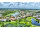 Expansive aerial shot of a community featuring shimmering lakes and verdant golf courses under a bright sky at 1210 Eagles Flight Way, North Port, FL 34287