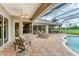 Outdoor patio seating with ceiling fan, pool, and screened lanai at 1210 Eagles Flight Way, North Port, FL 34287