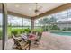 Covered patio with ceiling fan features an outdoor dining set and views of the pool and lake at 1210 Eagles Flight Way, North Port, FL 34287