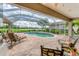 A screened-in pool with comfortable lounge chairs overlooks a lush green lawn and sparkling lake at 1210 Eagles Flight Way, North Port, FL 34287
