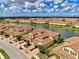 Aerial scene capturing a lakefront community featuring tan townhomes with red tile roofs at 12590 Ghiberti Cir # 201, Venice, FL 34293