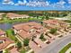 Wide aerial view of tan townhomes with brick driveways set by a lake and lush landscape at 12590 Ghiberti Cir # 201, Venice, FL 34293