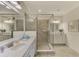 Well-lit bathroom boasts a glass shower enclosure, dual vanities, and modern fixtures at 12590 Ghiberti Cir # 201, Venice, FL 34293