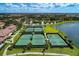 Aerial view of tennis courts and lush green landscaping next to a scenic lake at 12590 Ghiberti Cir # 201, Venice, FL 34293