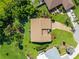 Aerial shot of a single-story home with a brown roof, lush greenery, and a driveway leading to the street at 1315 Pine Needle Rd, Venice, FL 34285