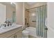 Well-lit bathroom featuring a single sink vanity with marble countertop and a shower-tub combo with coastal-themed curtain at 13334 Pacchio St, Venice, FL 34293