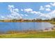 Scenic lake view showcasing waterfront homes with vibrant green lawns under a sunny, partly cloudy sky at 13334 Pacchio St, Venice, FL 34293