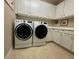 A bright laundry room with white cabinets and modern, front-load washer and dryer at 13334 Pacchio St, Venice, FL 34293