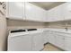 Bright laundry room with white washer, dryer, cabinets, countertops, and sink offering efficient utility space at 13334 Pacchio St, Venice, FL 34293