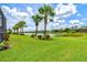 Picturesque backyard with a scenic lake view, lush green grass, and mature palm trees at 13913 Alafaya St, Venice, FL 34293