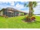 Backyard featuring a screened-in lanai with seating and a lush green lawn with beautiful landscaping at 13913 Alafaya St, Venice, FL 34293