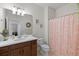 Well-lit bathroom with wood vanity, decorative mirror, and patterned shower curtain at 13913 Alafaya St, Venice, FL 34293