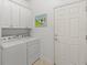 Functional laundry area equipped with washer, dryer, cabinetry, and exterior access door at 13913 Alafaya St, Venice, FL 34293