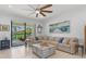 Bright living room with ceiling fan opens to brick patio and manicured backyard with lush landscaping at 13913 Alafaya St, Venice, FL 34293