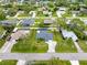 Aerial view of a home with a screened-in pool, lush landscaping, and a charming neighborhood setting at 1536 Porpoise Rd, Venice, FL 34293