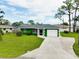 Inviting single-story home with a well-maintained lawn, a driveway and a charming green exterior at 1536 Porpoise Rd, Venice, FL 34293